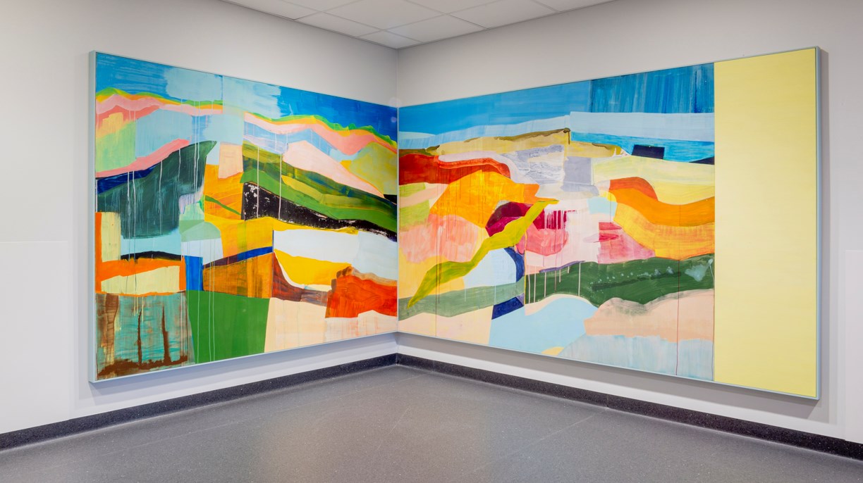 Två stora målningar placerade mot vita väggar i ett hörn