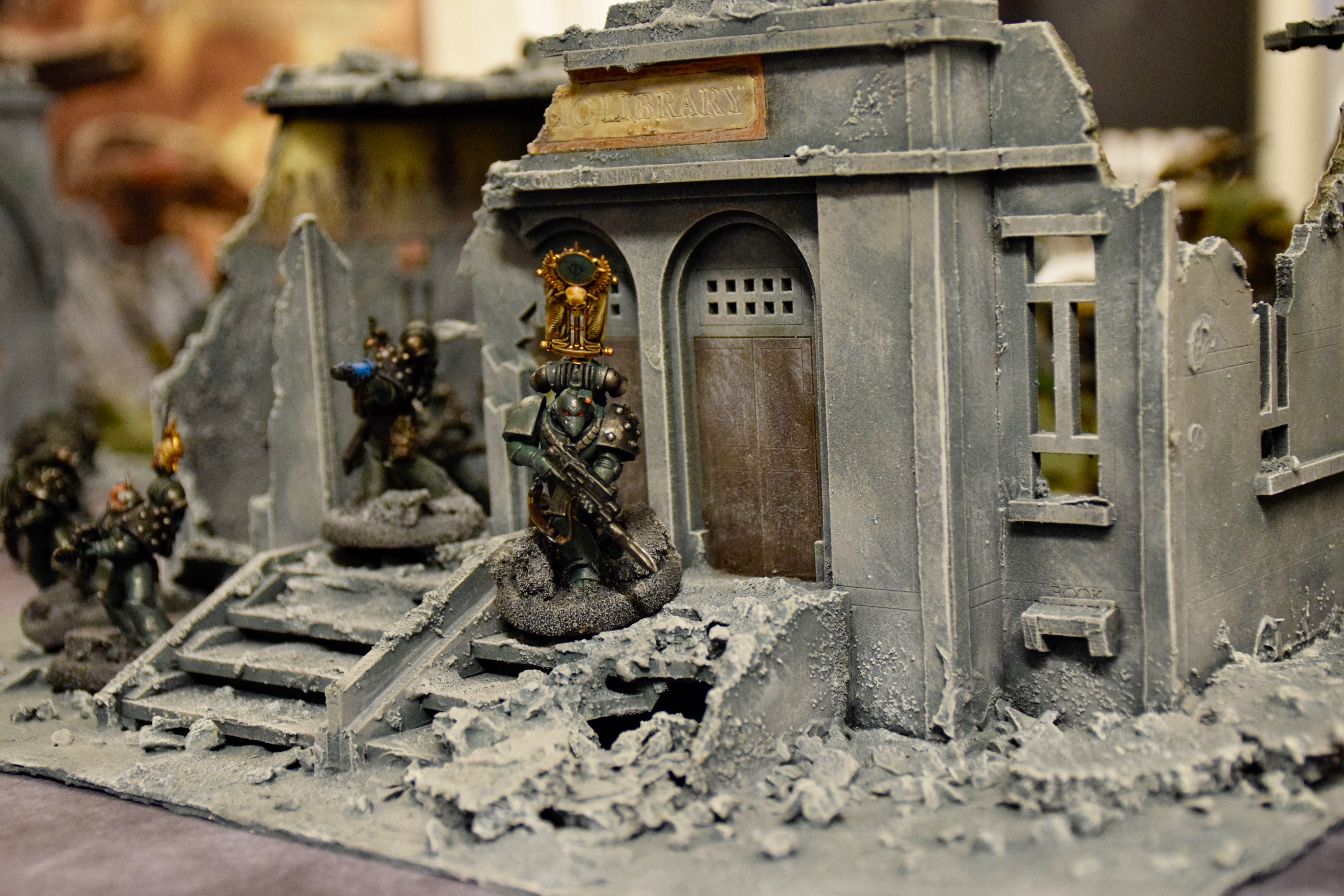 En spelfigur med vapen står utanför ett raserat bibliotek. 