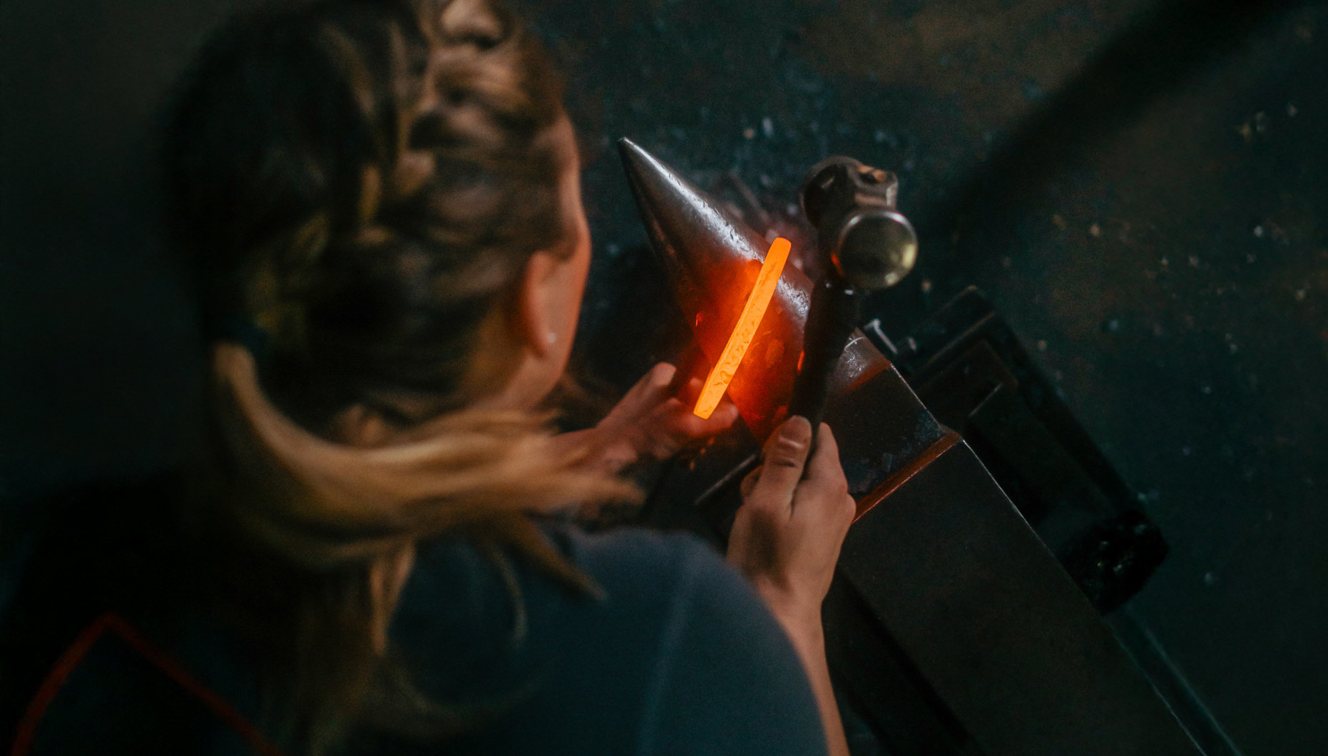 Tjej med flätat hår håller i hammare och glödande hästsko