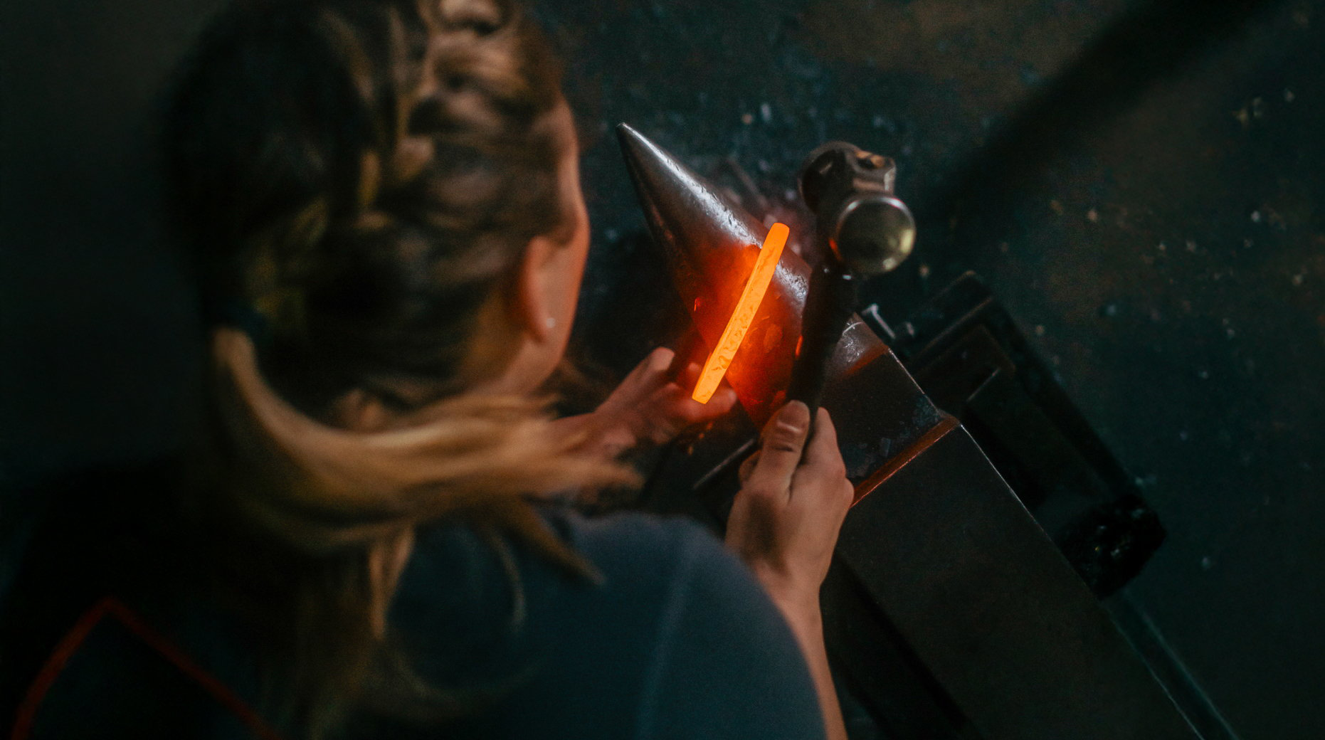 Vy ovanifrån där hovslagare håller i hammare och glödande hästsko